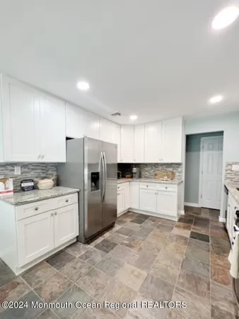 a large white kitchen with a stove a refrigerator and a sink