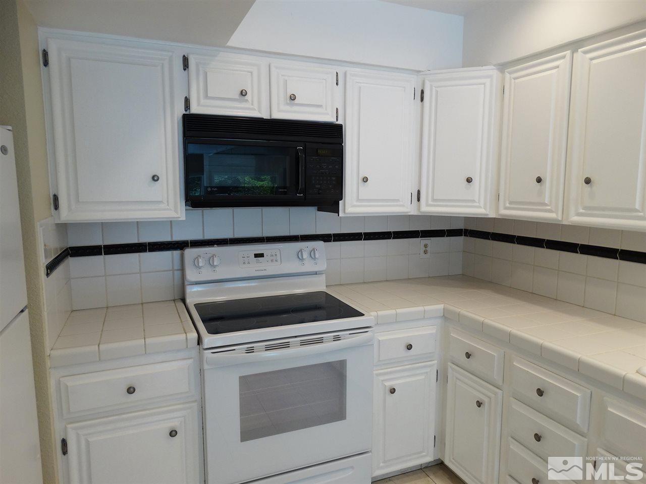 1336 Jones Street Reno, NV 89503 - Photo 9 of 24 a kitchen with white cabinets and black appliances