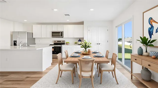 a dining room with furniture a potted plant and a kitchen view