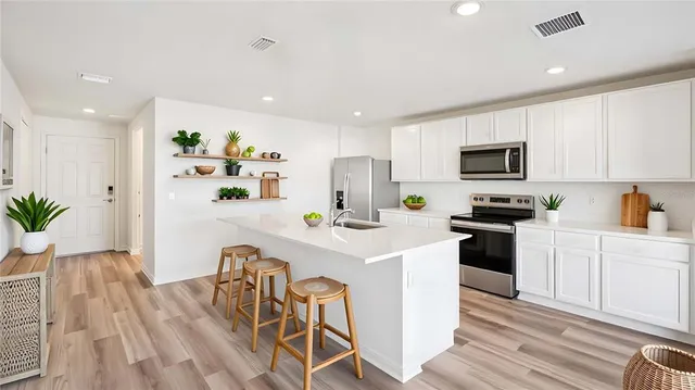 a kitchen with stainless steel appliances a microwave sink refrigerator and cabinets