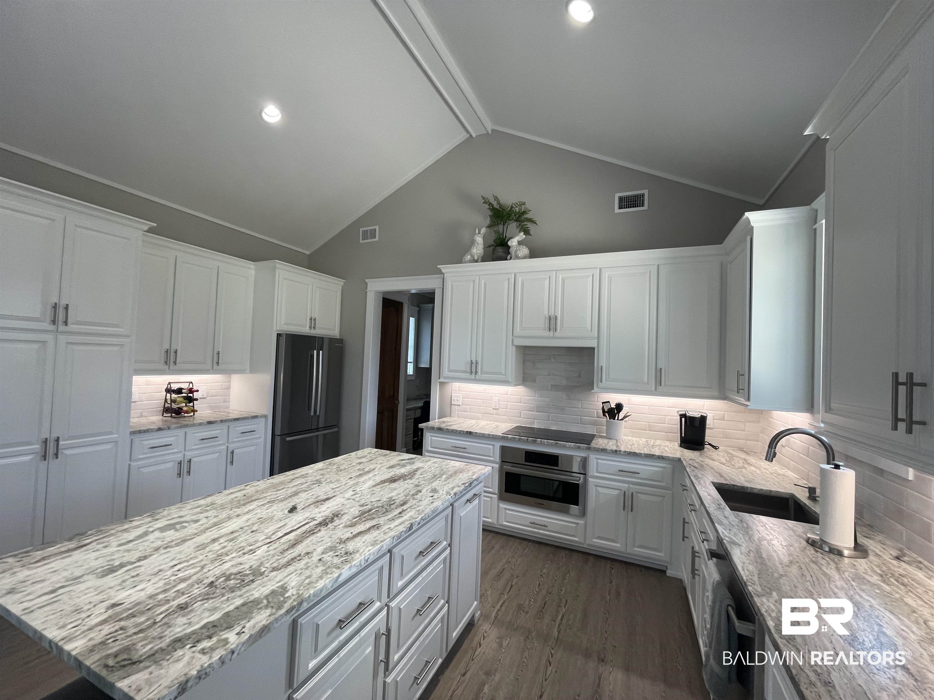 6 Fairhope Motorcoach Loop Fairhope, AL 36532 - Photo 10 of 33 Kitchen featuring stainless steel appliances, white cabinetry, lofted ceiling, and decorative backsplash