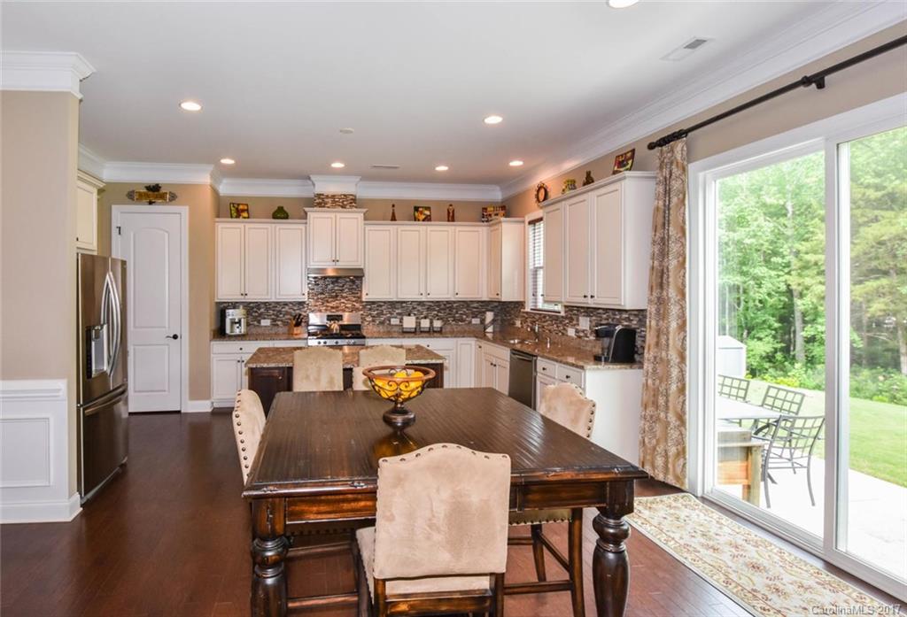 6004 Fallondale Road, Unit 881 Waxhaw, NC 28173 - Photo 9 of 20 a kitchen with stainless steel appliances granite countertop sink refrigerator dining table and chairs