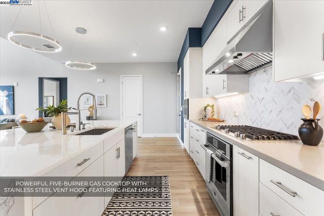 a large white kitchen with a large island oven a stove with wooden floors