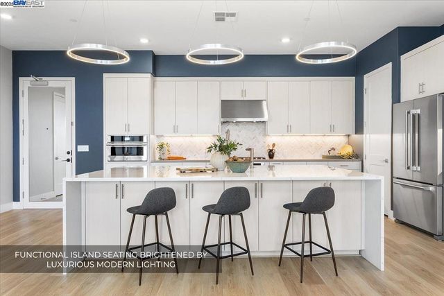 a living room with furniture kitchen view and a wooden floor