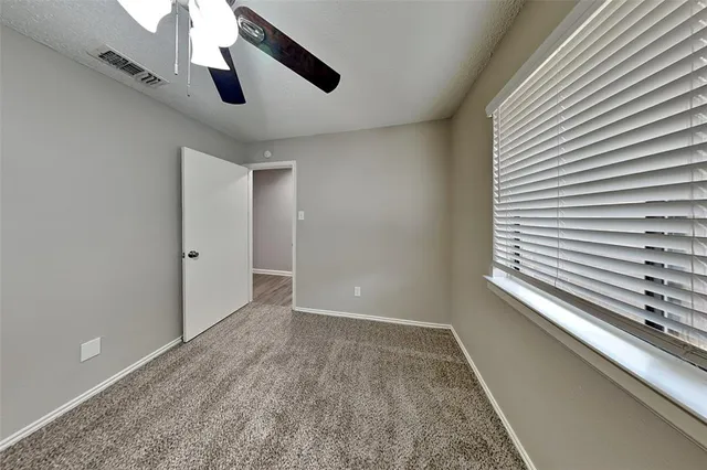 an empty room with a ceiling fan and carpet