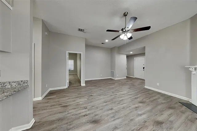 a view of an empty room and window with a ceiling fan