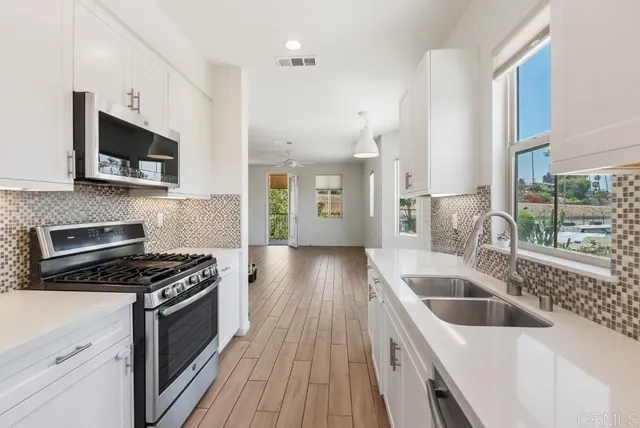a kitchen with granite countertop a sink a counter space stainless steel appliances and cabinets