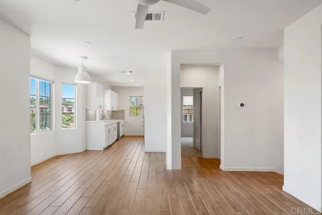 a view of a hallway with wooden floor and a kitchen