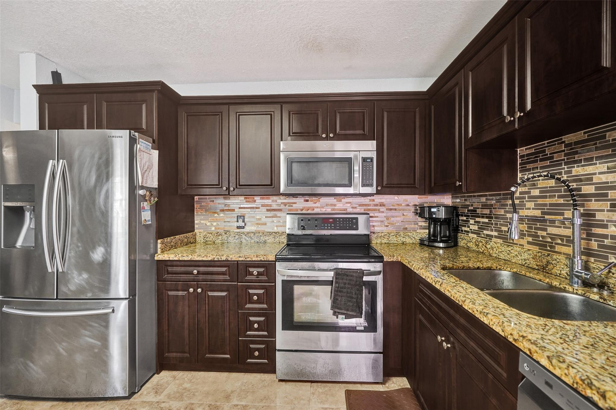 8740 Azalea Court, Unit 102 Tamarac, FL 33321 - Photo 38 of 60 a kitchen with granite countertop a refrigerator stove and microwave
