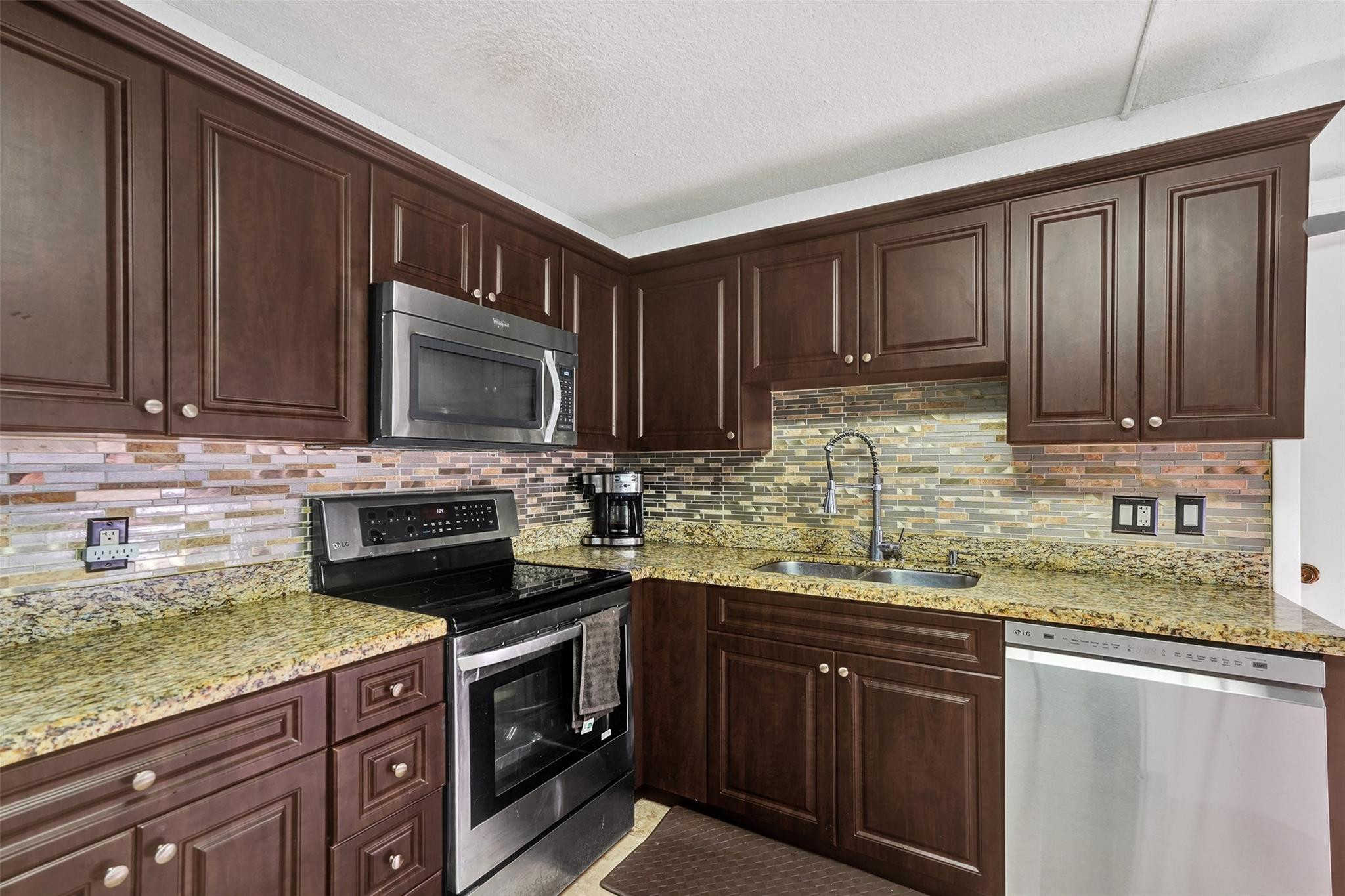 8740 Azalea Court, Unit 102 Tamarac, FL 33321 - Photo 39 of 60 a kitchen with granite countertop stainless steel appliances a stove a sink and a microwave