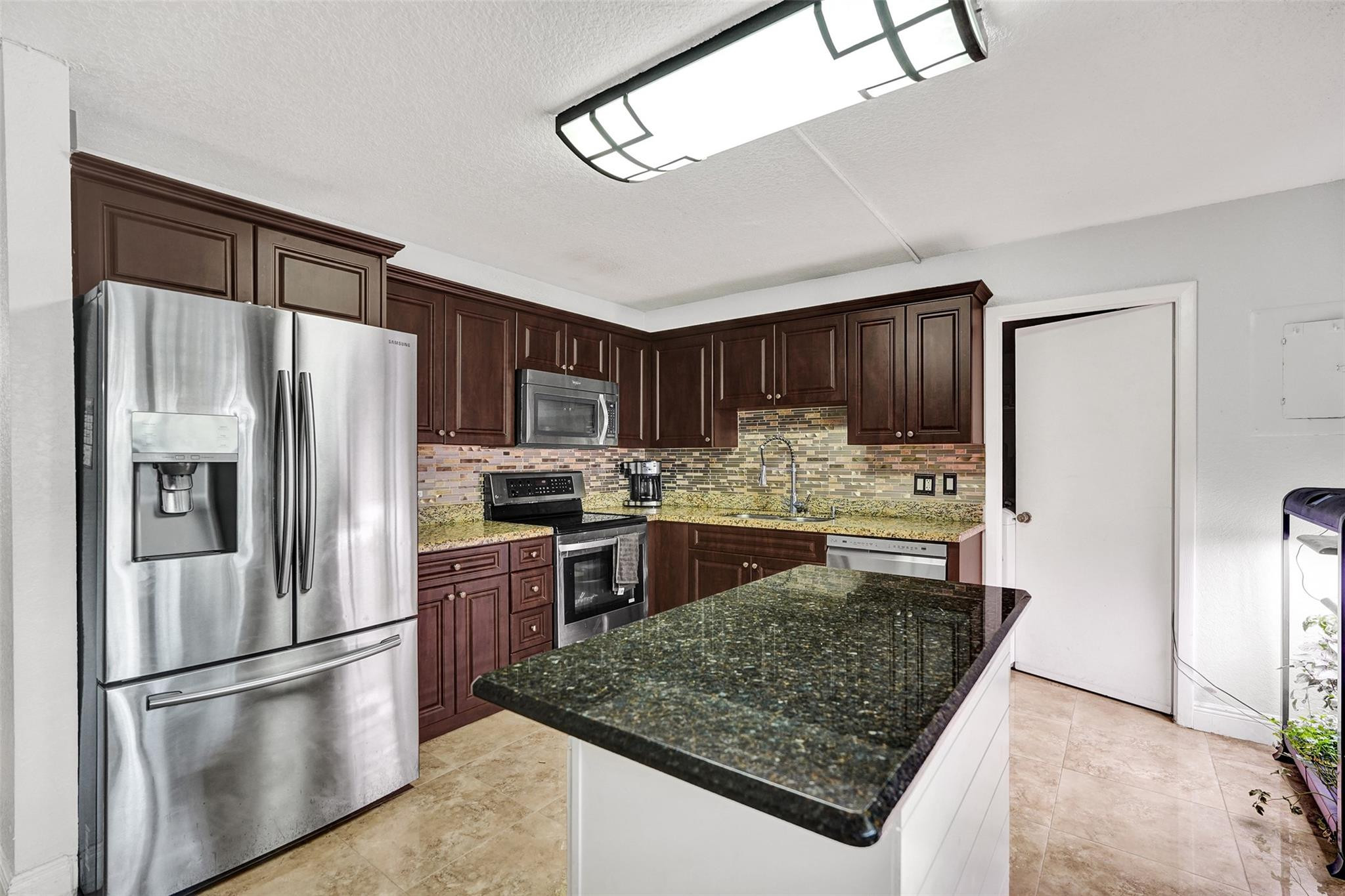 8740 Azalea Court, Unit 102 Tamarac, FL 33321 - Photo 7 of 60 a kitchen with stainless steel appliances granite countertop a refrigerator stove and oven