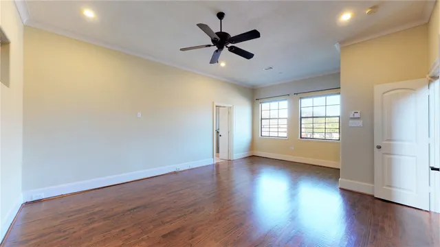 an empty room with wooden floor fan and windows