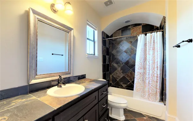 a bathroom with a granite countertop sink toilet and shower