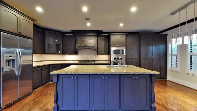 a kitchen with kitchen island granite countertop wooden cabinets and stainless steel appliances