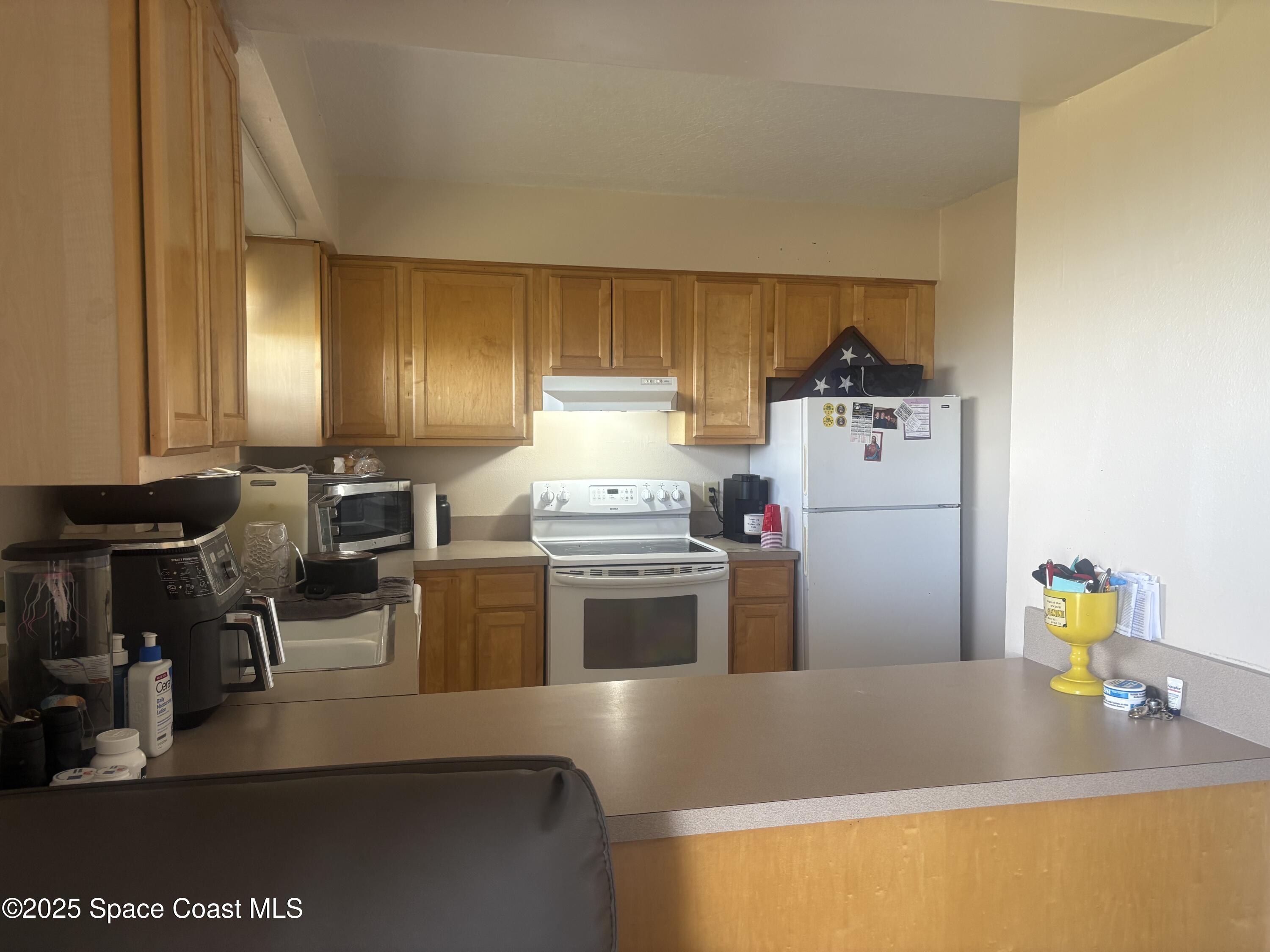 3150 North Atlantic Avenue, Unit 7550 Cocoa Beach, FL 32931 - Photo 3 of 4 a kitchen with a refrigerator and a stove top oven
