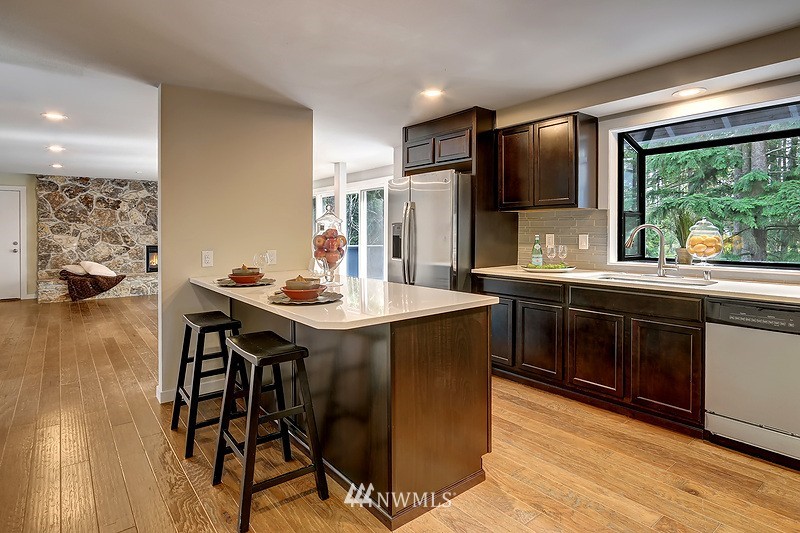 4304 181st Street Southeast Bothell, WA 98012 - Photo 3 of 18 a kitchen with stainless steel appliances granite countertop a sink a stove a refrigerator and a dining table with wooden floor
