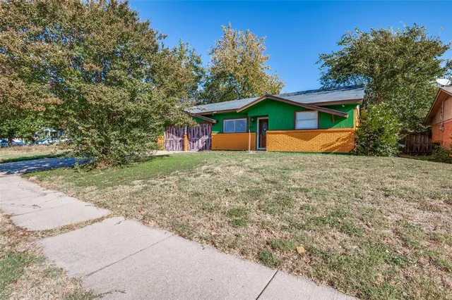 a view of a house with a yard and large tree