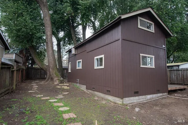 a backyard of a house with large trees and parked
