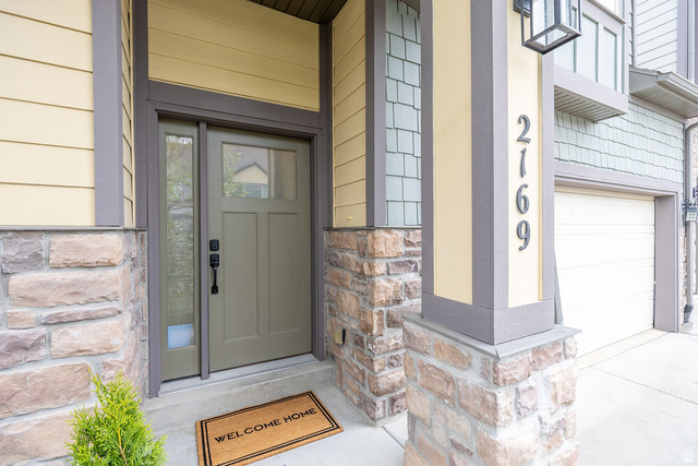 2169 Orchard Pines Loop East Bountiful, UT 84010 - Photo 31 of 32 Exterior entry with a paneled door and sidelight, complemented by horizontal siding and stone veneer accents
