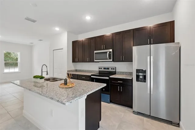a kitchen with granite countertop kitchen island a refrigerator stove and sink