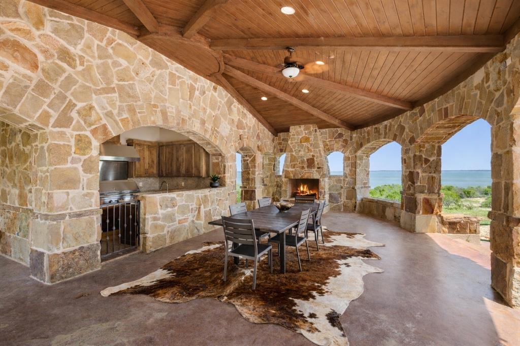 1180 McReynolds Road Sanger, TX 76266 - Photo 29 of 40 Stone-clad outdoor living area featuring a vaulted wood-plank ceiling, stone fireplace, and built-in outdoor kitchen with stainless steel appliances
