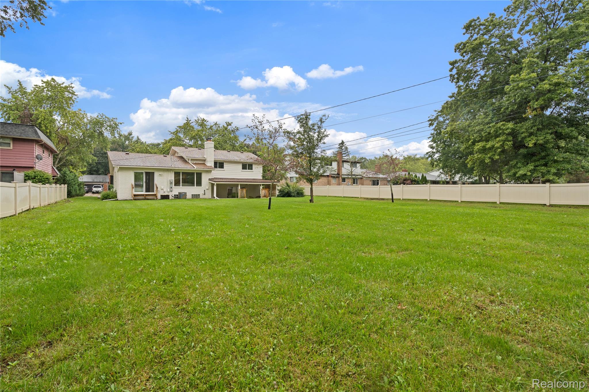 8240 Hampton Road Grosse Ile, MI 48138 - Photo 30 of 33 Expansive rear lawn featuring a privacy fence, established trees, and a rear patio