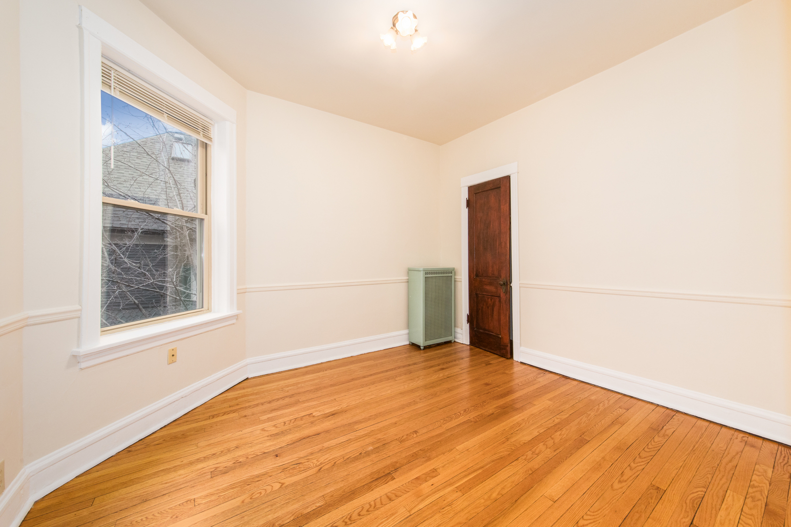 4117 North Paulina Street Chicago, IL 60613 - Photo 16 of 28 a view of an empty room with wooden floor and a window