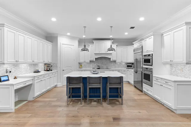 a kitchen with a sink stove and white cabinets with wooden floor