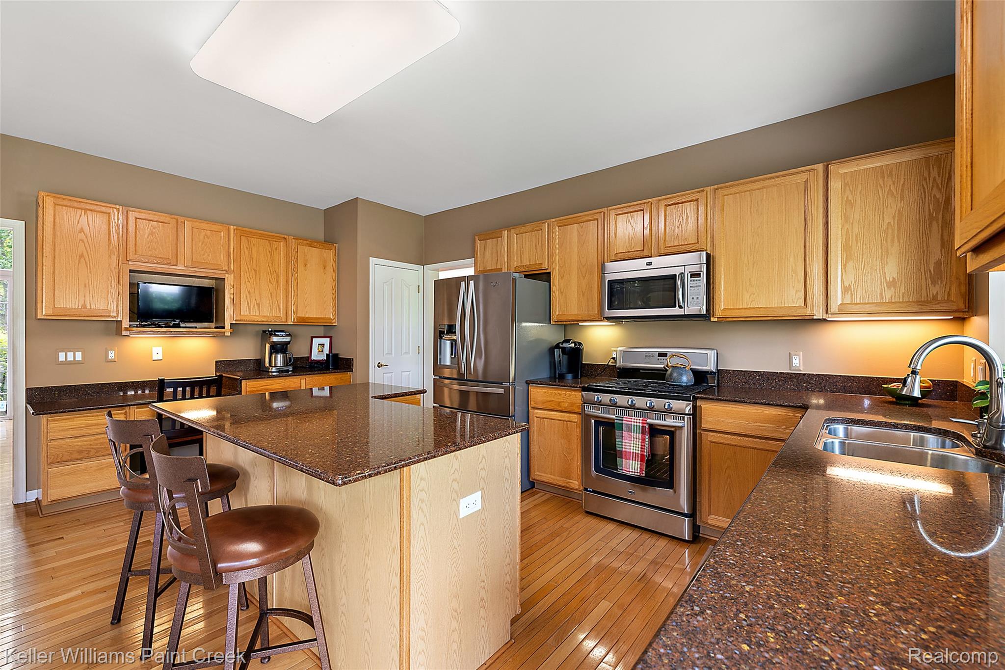 1933 Catlin Drive Rochester, MI 48306 - Photo 13 of 54 Kitchen featuring appliances with stainless steel finishes, light wood-type flooring, a kitchen island, dark stone counters, and a breakfast bar