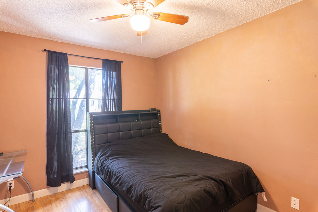 5310 Presidio Road Austin, TX 78745 - Photo 18 of 34 Well-lit sleeping quarters with a ceiling fan, featuring durable hardwood flooring and a bright window.