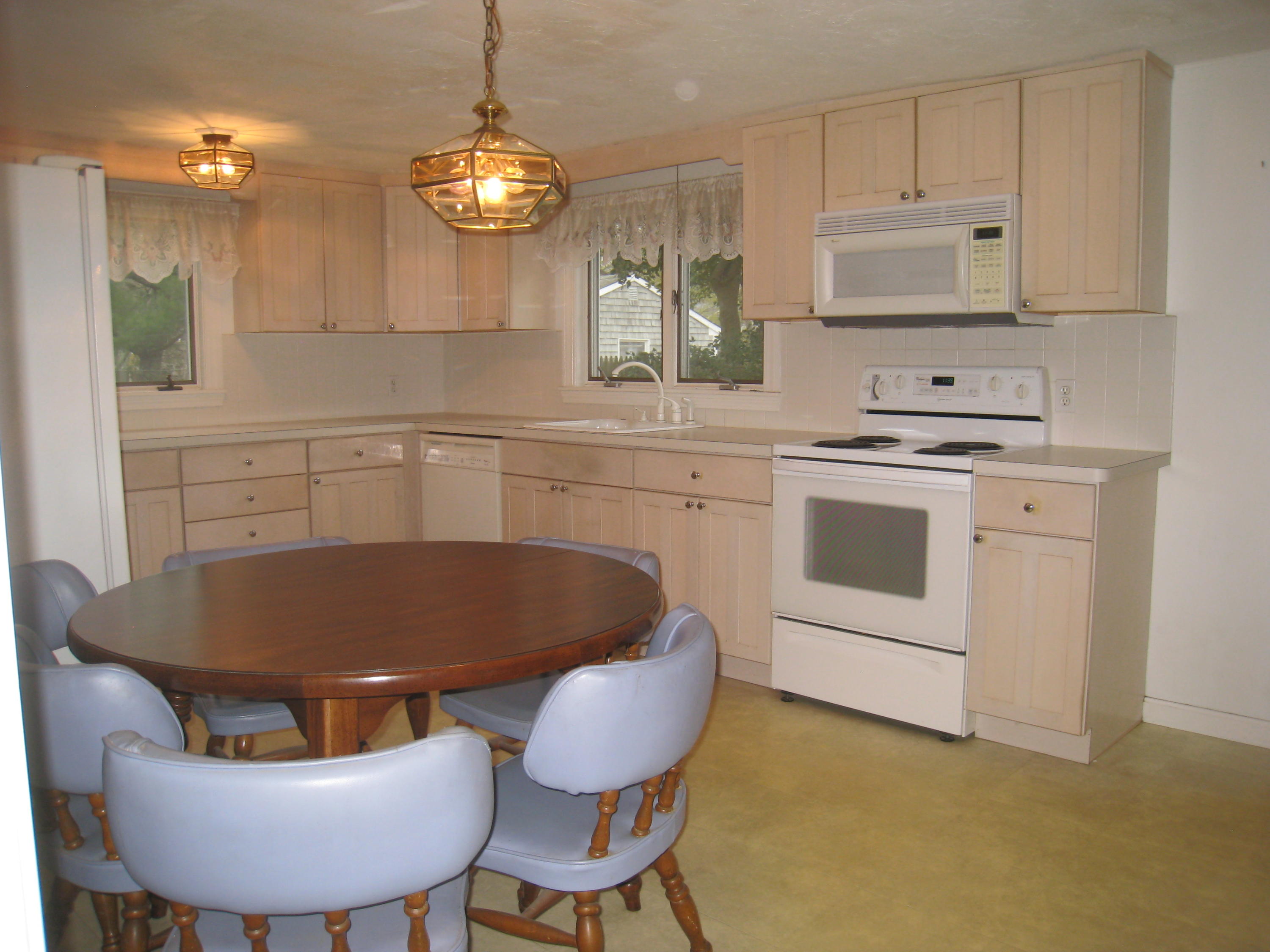 34 Tevyaw Road Hyannis, MA 02601 - Photo 19 of 28 a kitchen with stainless steel appliances granite countertop a sink a stove a microwave a dining table and chairs