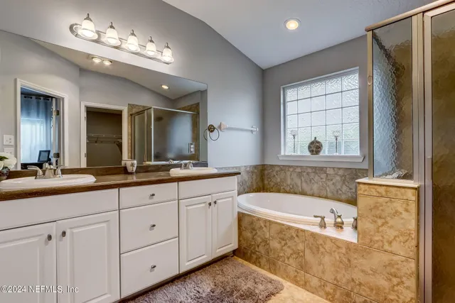 a bathroom with a tub a double vanity sink a vanity and a large mirror