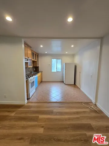 a view of kitchen and empty room with wooden floor