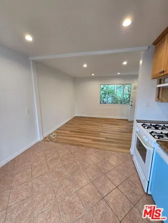 a view of kitchen and empty room with wooden floor