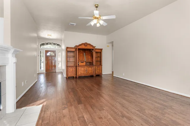 a view of a room with wooden floor and a ceiling fan