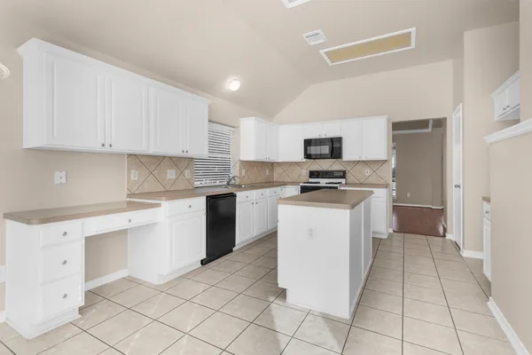 a kitchen with granite countertop white cabinets and stainless steel appliances
