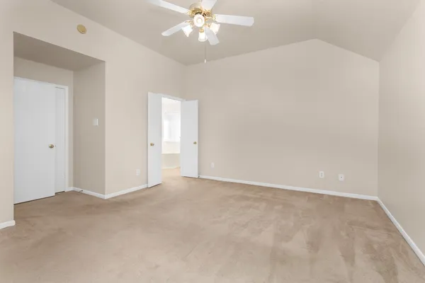a view of an empty room with a chandelier fan
