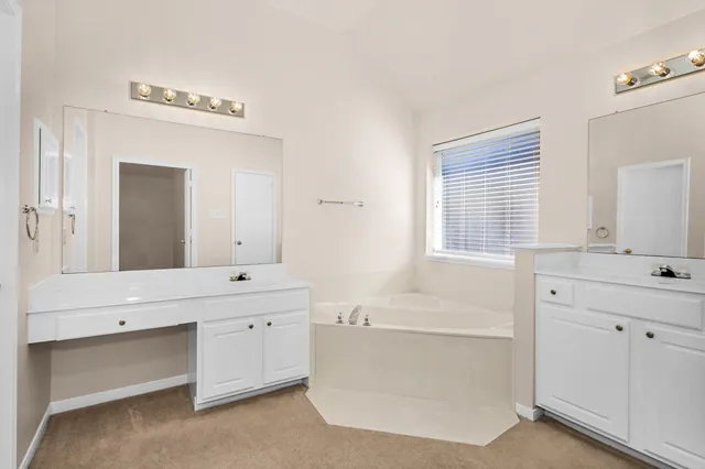 a spacious bathroom with a double vanity sink mirror and bathtub