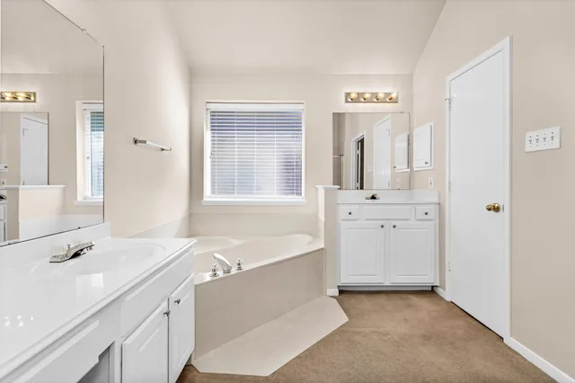 a spacious bathroom with a double vanity sink a mirror and a bathtub