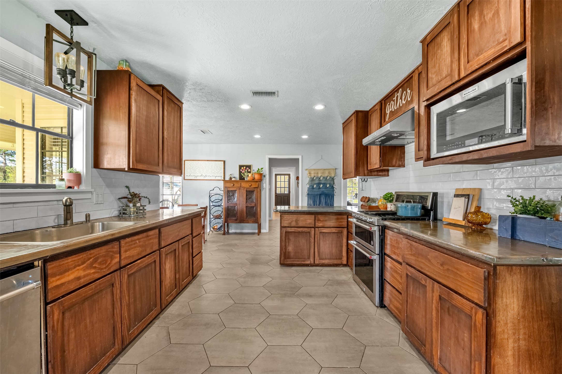 26515 Dobbin-Huffsmith Road Magnolia, TX 77354 - Photo 16 of 47 a large kitchen with stainless steel appliances granite countertop a stove top oven a sink dishwasher a dining table and chairs with wooden cabinets