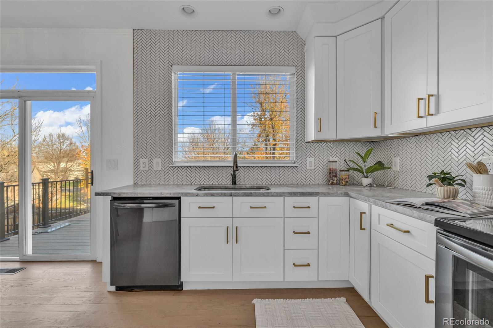 8204 Swadley Street Arvada, CO 80005 - Photo 12 of 39 a kitchen with granite countertop white cabinets and white appliances