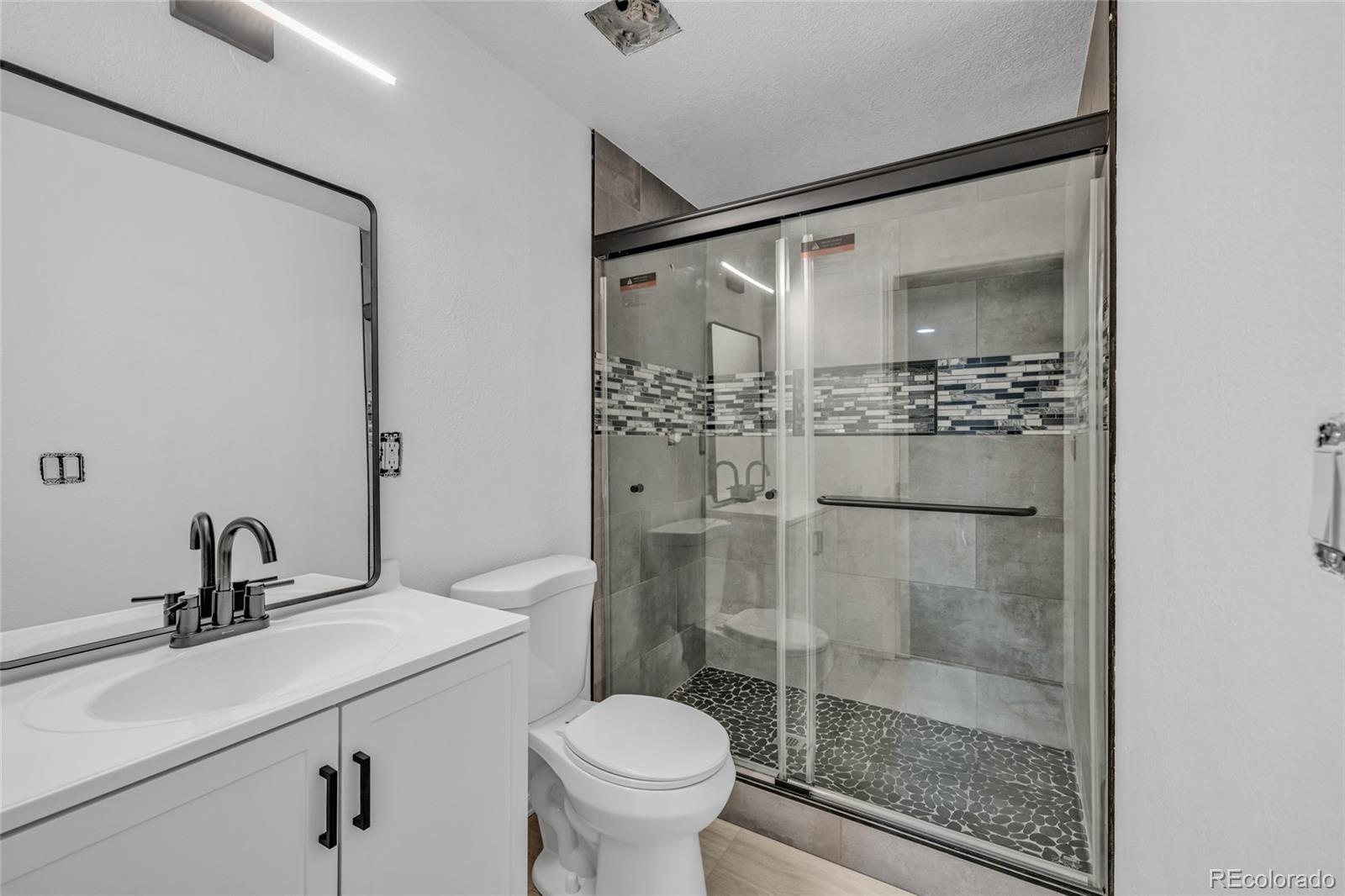 8204 Swadley Street Arvada, CO 80005 - Photo 25 of 39 a bathroom with a shower sink mirror and toilet