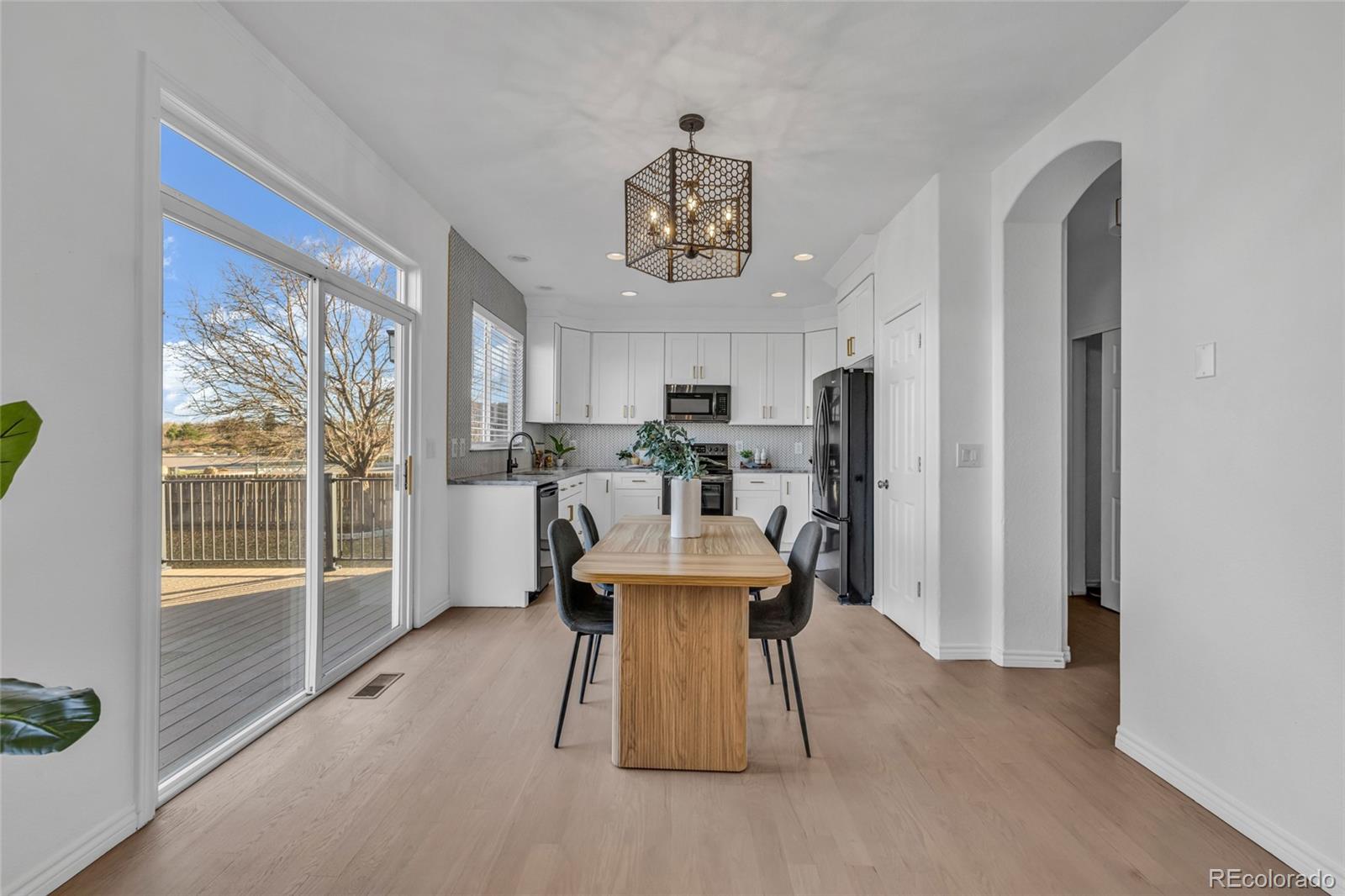 8204 Swadley Street Arvada, CO 80005 - Photo 10 of 39 a living room with a couch and a dining table with kitchen view