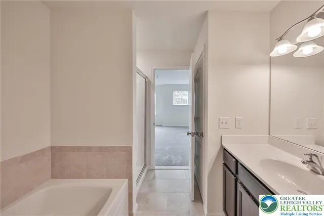 a bathroom with a tub sink vanity granite and shower