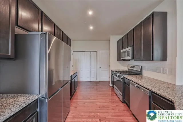 a kitchen with stainless steel appliances granite countertop a refrigerator a sink and wooden cabinets