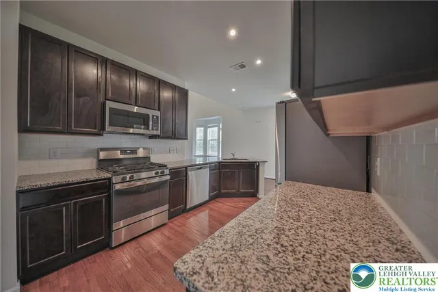 a kitchen with stainless steel appliances granite countertop a stove a sink and a refrigerator