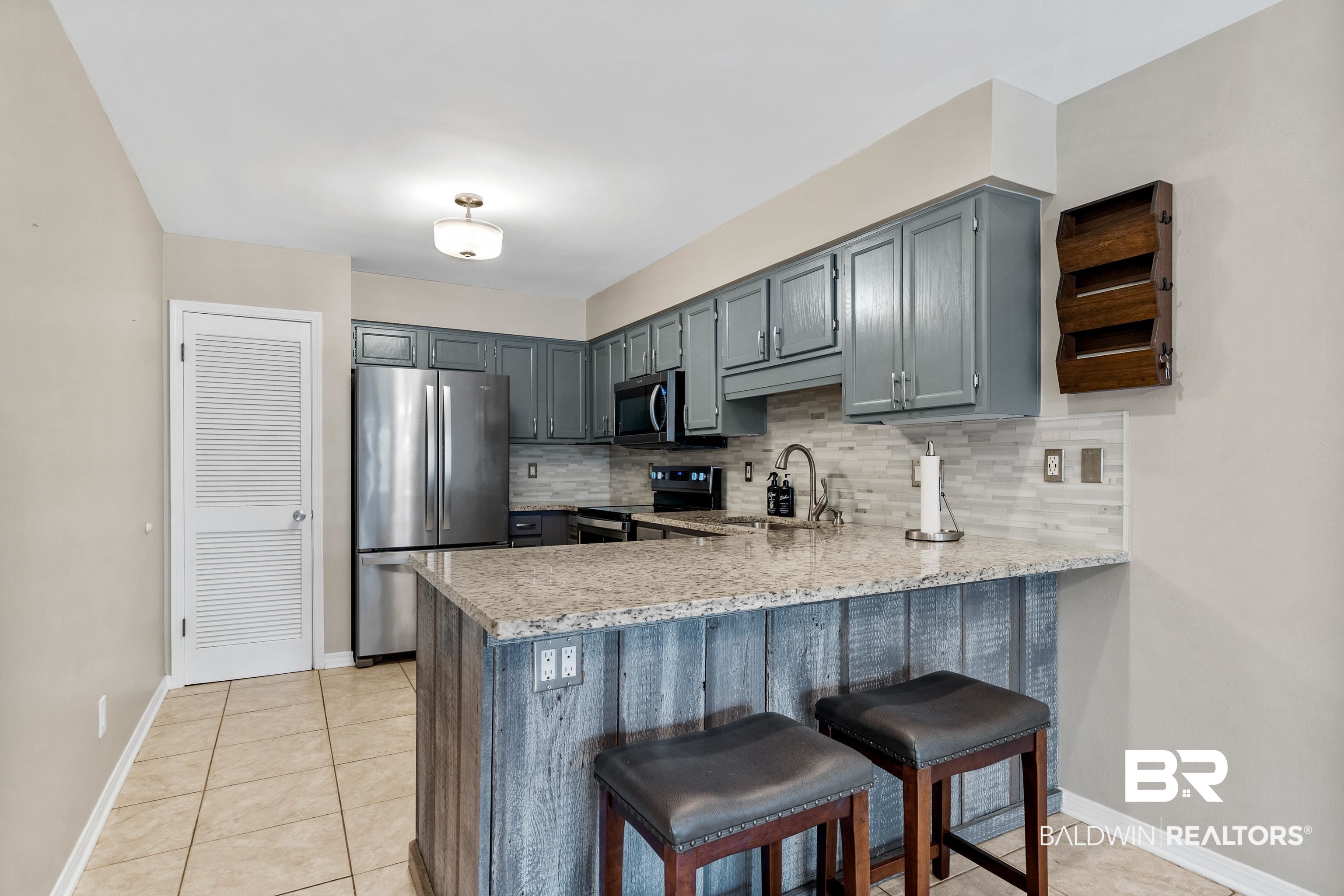 1701 Regency Road, Unit 111 Gulf Shores, AL 36542 - Photo 11 of 29 Kitchen featuring kitchen peninsula, stainless steel appliances, and backsplash
