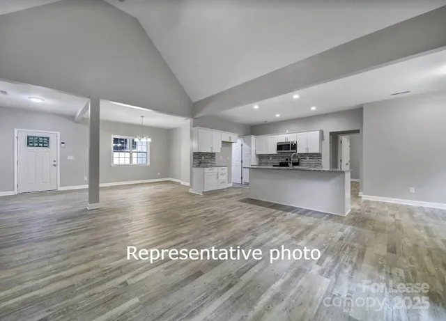 a view of kitchen and empty room with wooden floor
