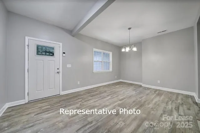 a view of an empty room with window and wooden floor