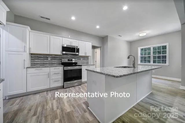 a kitchen with granite countertop a stove top oven and cabinets